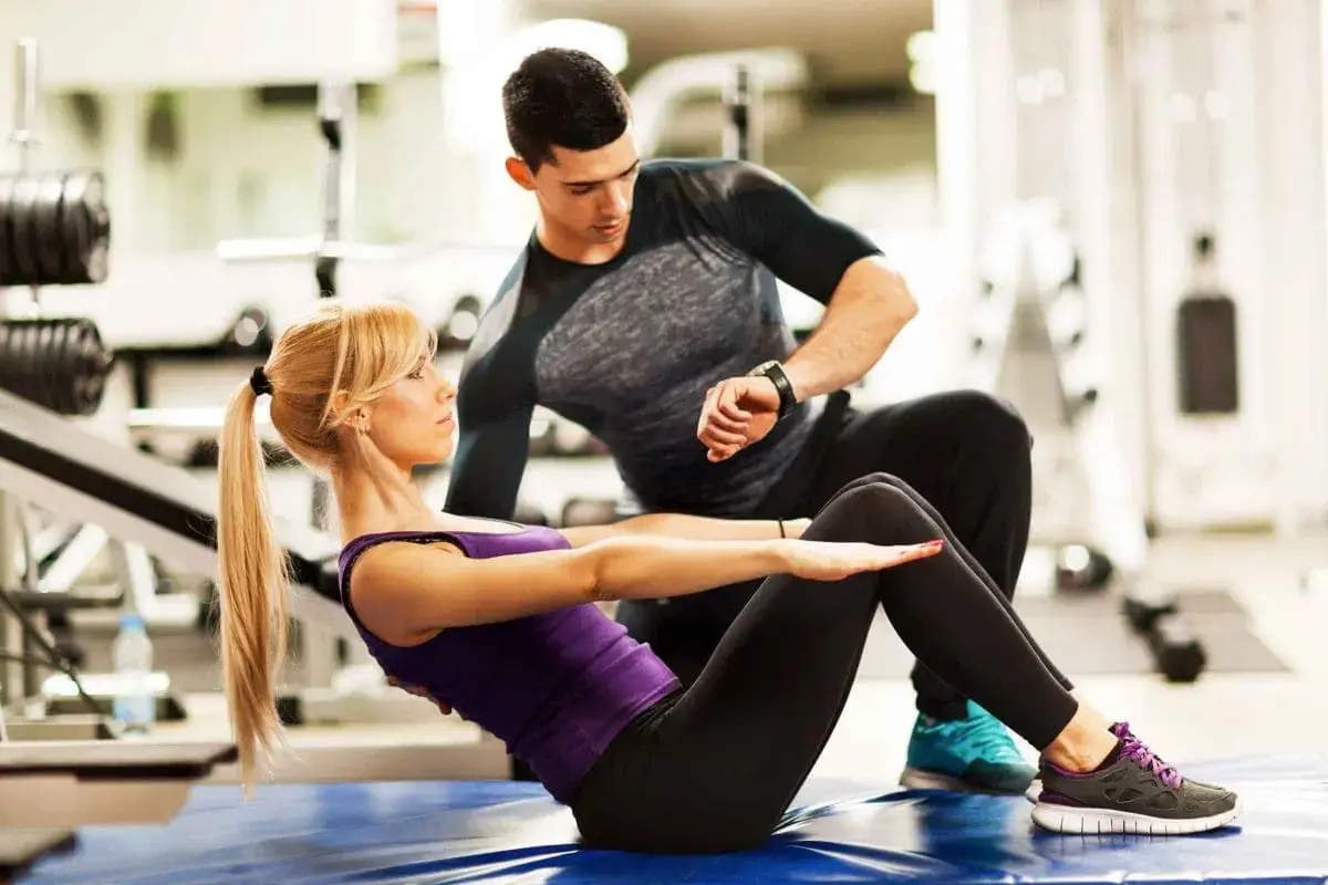 Trainer assisting a member with their form